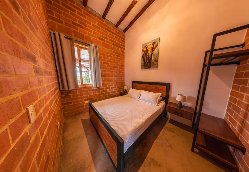 Dormitorio del apartamento con cama doble y paredes de ladrillo