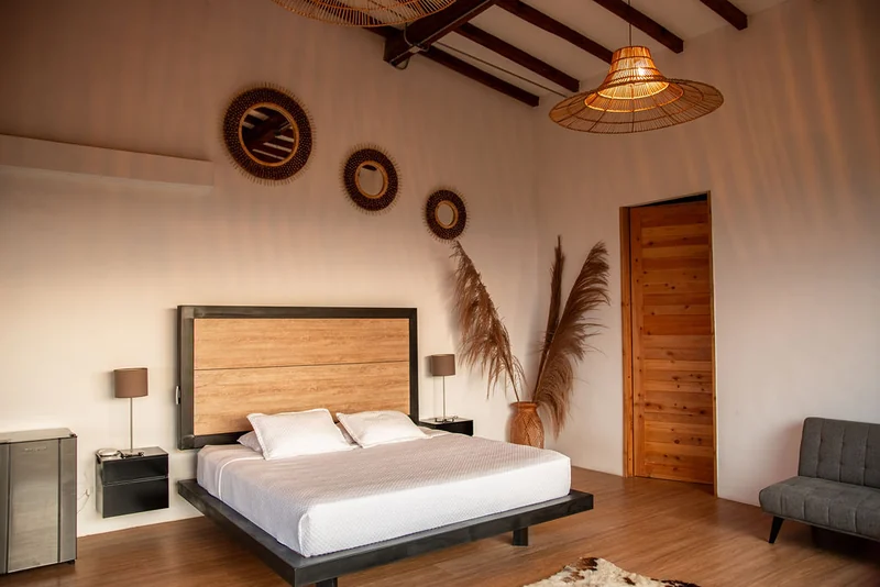 Cama de la suite con cabecero de madera y techo de vigas