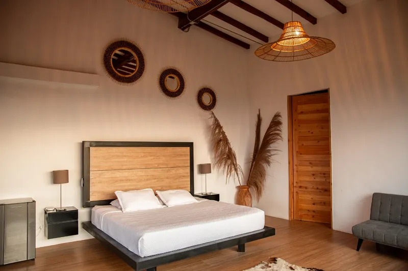 Suite con cama king, mesas de noche y decoración en madera — Finca Hotel Los Balcones, Filandia